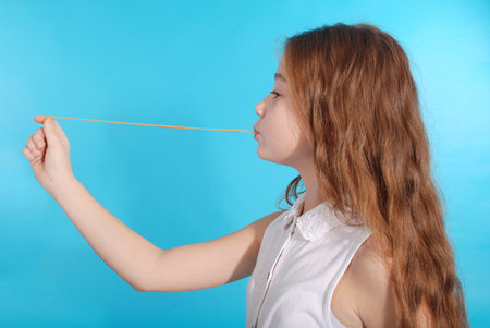 Young girl playing with chewing gum isolated on blue