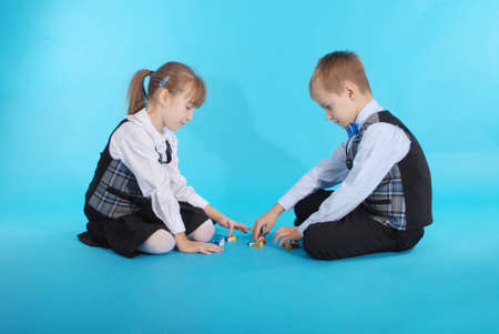 Schoolboy and schoolgirl playing with candy. Photos on a blue backgroundの写真素材