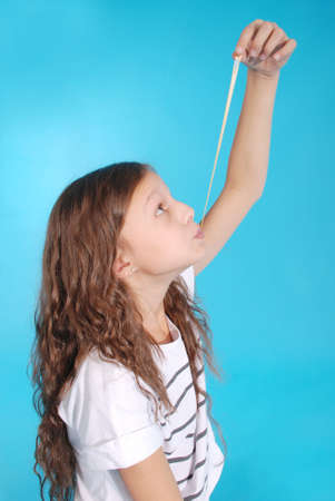 Young girl playing with chewing gum isolated on blueの写真素材