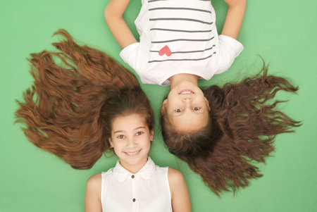 Portrait of two young girls with long hair, top view, isolated on green