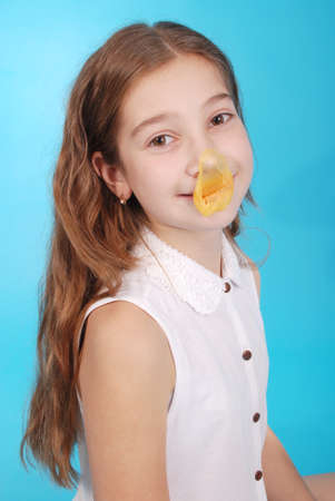 Young girl playing with chewing gum isolated on blueの写真素材
