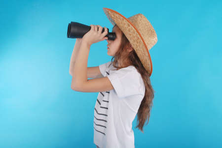 Young girl with binoculars isolated on blue backgroundの写真素材