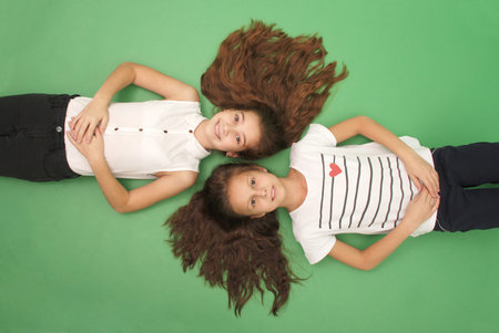 Portrait of two young girls with long hair, top view, isolated on greenの写真素材