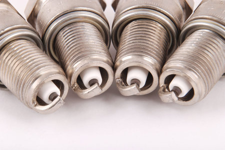 Four new spark plugs on a gray background