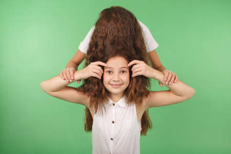 Funny portrait of two young girls with long hair isolated on greenの写真素材