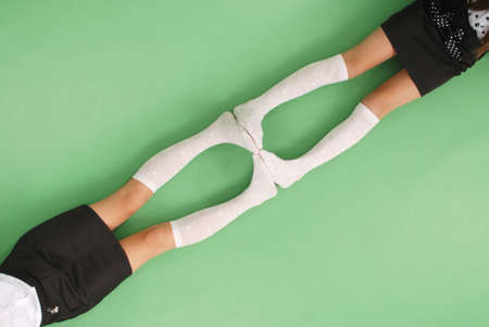 Two girls in knee-length socks isolated on green backgroundの写真素材