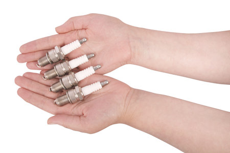 Four spark plugs in the open palms on a isolated white background. Photo with clipping path