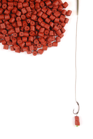 Fishing bait with hook and red pre-drilled halibut pellets for carp fishing isolated on white background with soft shadowの写真素材