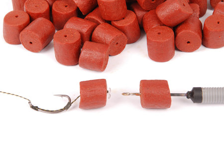 Fishing bait with hook and red pre-drilled halibut pellets for carp fishing isolated on white...