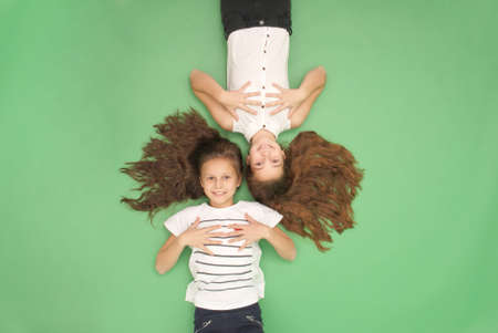Portrait of two young girls with long hair, top view, isolated on greenの写真素材