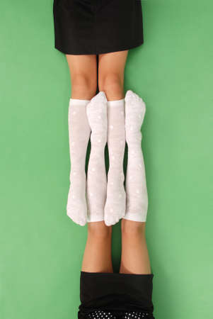 Two girls in knee-length socks isolated on green backgroundの写真素材