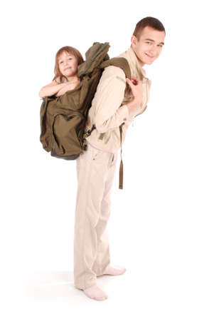 Teenager holds on the shoulders of a little girl looking out a large backpack isolated on white backgroundの写真素材