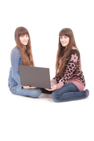 Portrait of two twins sisters with laptop on white backgroundの写真素材