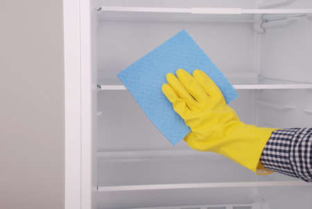 Young girl cleaning empty fridge with a sponge. Beautiful young girl near the fridge.の写真素材