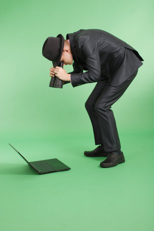 Full length portrait of confident mature businessman which looks through binoculars in laptop in...