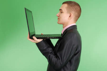 Full length portrait of confident mature businessman which working on laptop in formals standing isolated over green backgroundの写真素材