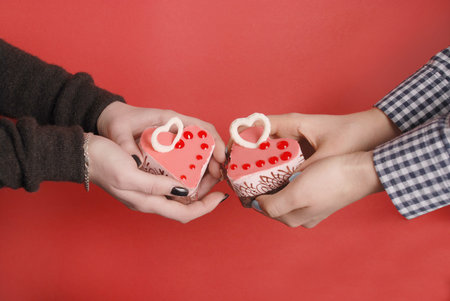 Female hands keep heart-shape cake with candle. Isolated on redの写真素材