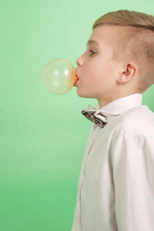 Boy blowing a bubblegum bubble isolated on greenの写真素材