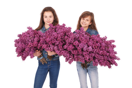 Two girls teenager standing with lilac in hands. Isolated on a white backgroundの写真素材