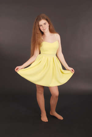Young girl in yellow dress isolated on black backgroundの写真素材