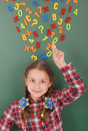 Girl stands in front of a green school board with magnets of figures that depict her thoughts on white backgroundの写真素材