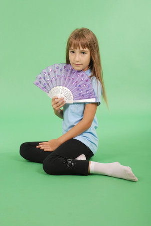 Young girl with light hair holding pink lace fan in hand isoalted on green backgroundの写真素材