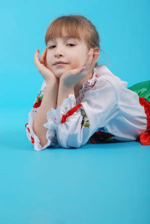 Young girl with light hair in Ukrainian embroidery isolated on blue backgroundの写真素材