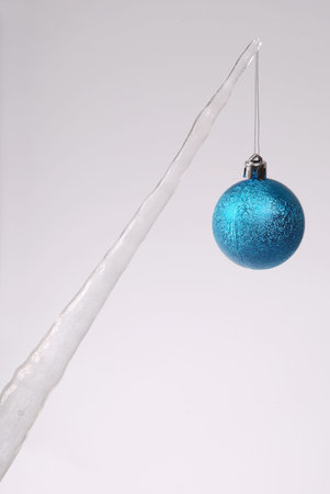 Icicle with a Christmas tree toy isolated on a grey background. Frozen water.の写真素材