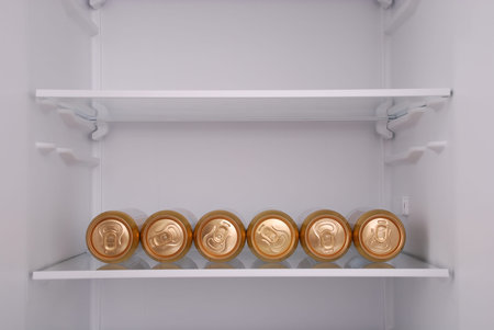 Six metal beer cans inside in empty clean refrigerator with opened doorの写真素材