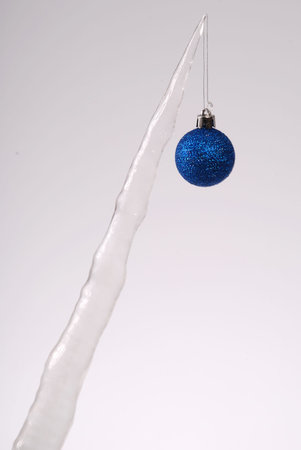 Icicle with a Christmas tree toy isolated on a grey background. Frozen water. の写真素材