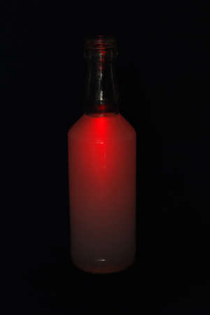 A bottle with a red drink on a black backgroundの写真素材