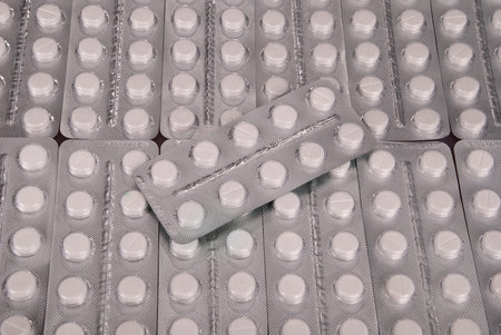 Plenty of white tablets in packing. Silver packs pills. Pills background