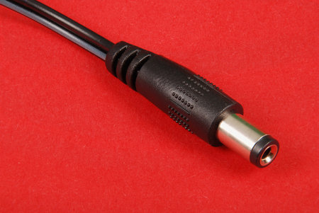Black plug of power charger of laptop isolated on red background