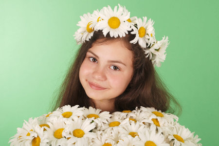 Beautiful girl with chamomile wreath on green background.の写真素材