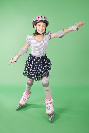 Pretty girl with rollerskates isolated against green backgroundの写真素材
