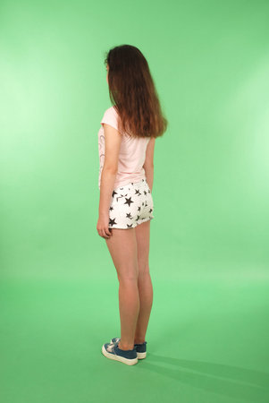 Side view young girl with long hair looking at wall. Isolated on green backgroundの写真素材