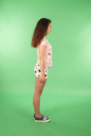 Side view young girl with long hair looking at wall. Isolated on green backgroundの写真素材