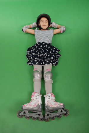 Pretty girl with rollerskates lying on green backgroundの写真素材