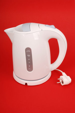 White electric kettle isolated on red backgroundの写真素材
