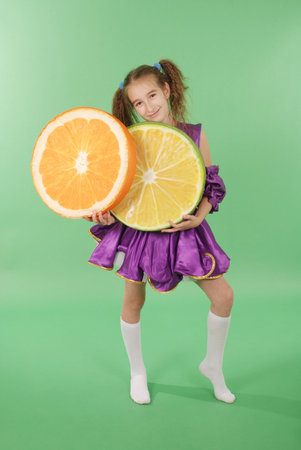 Pretty girl posing for the camera, in a violet short dress. Isolated on green.