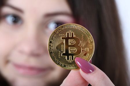Pretty Girl holding in front of her new golden cryptocurrency bitcoin in hands on white background....