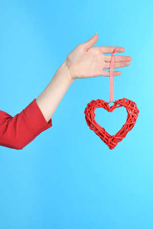 Woman hand holding symbol heart in hand isolated over blue backgroundの写真素材