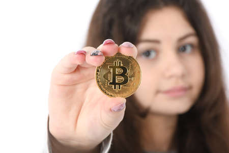 Pretty Girl holding in front of her new golden cryptocurrency bitcoin in hands on white background. Soft focusの写真素材