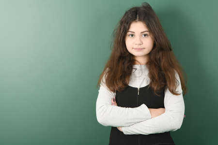 Smiling little schoolgirl folded hands green backgroundの写真素材