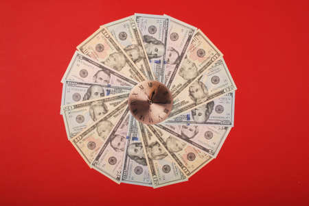 Concept of clock and dollar. Clock on mandala kaleidoscope from money. Abstract money background raster pattern repeat mandala circle. On red background.の写真素材