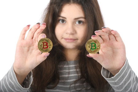 Pretty Girl holding new golden cryptocurrency bitcoin in hands on white background. Concept of bitcoin grows and falls in priceの写真素材