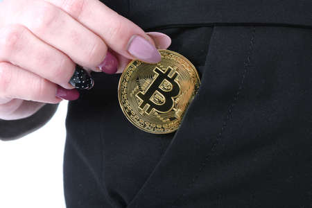 Pretty Girl puts it in her pocket golden cryptocurrency bitcoin in hands on white backgroundの写真素材