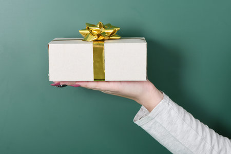 Hand holds white gift isolated on green backgroundの写真素材