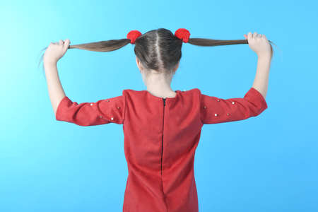 Full length studio photo girl wearing red dress standing on blue background. Back view.の写真素材