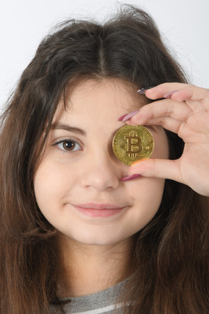 Pretty Girl holding in front of her new golden cryptocurrency bitcoin in hands on white background